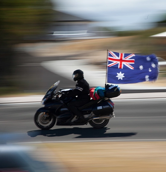 Man riding a motorcycle with Australia Flag in a blurred motion background